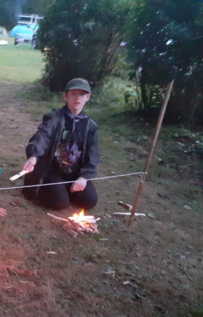 Scout tending a small campfire outdoors.