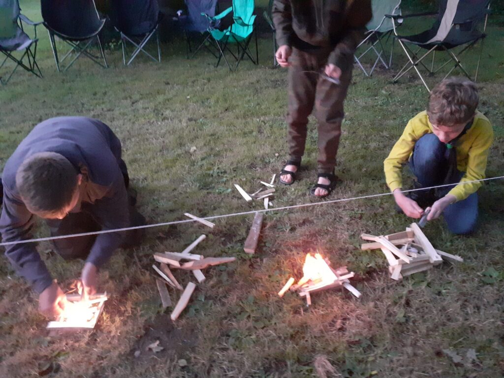 Scouts practising firelighting with sticks at camp.