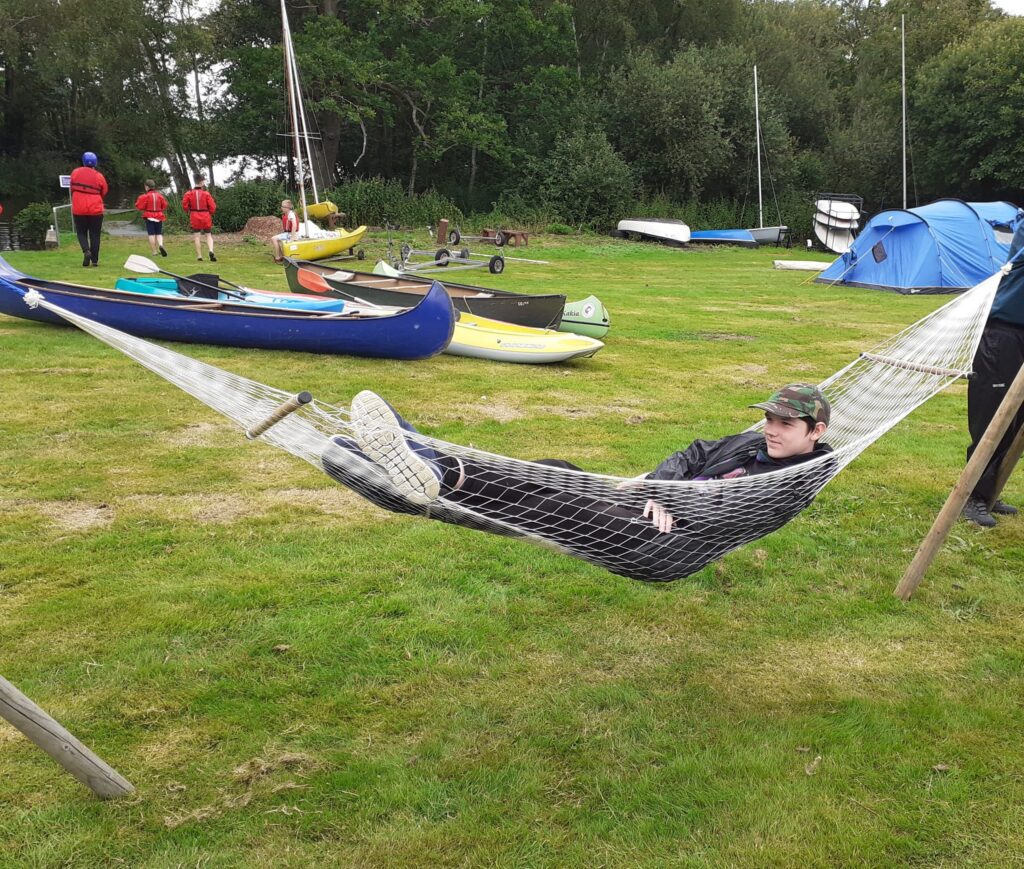 Scout relaxing in a hammock near the kayaks at camp.