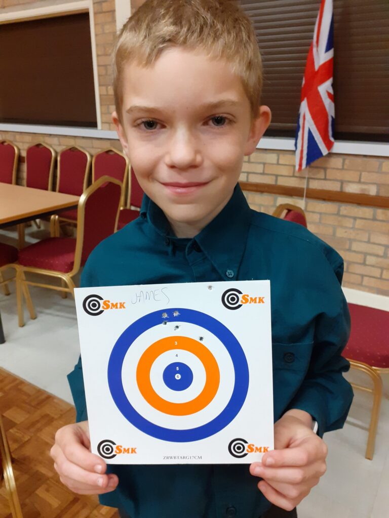 Scout in uniform holding a paper target.