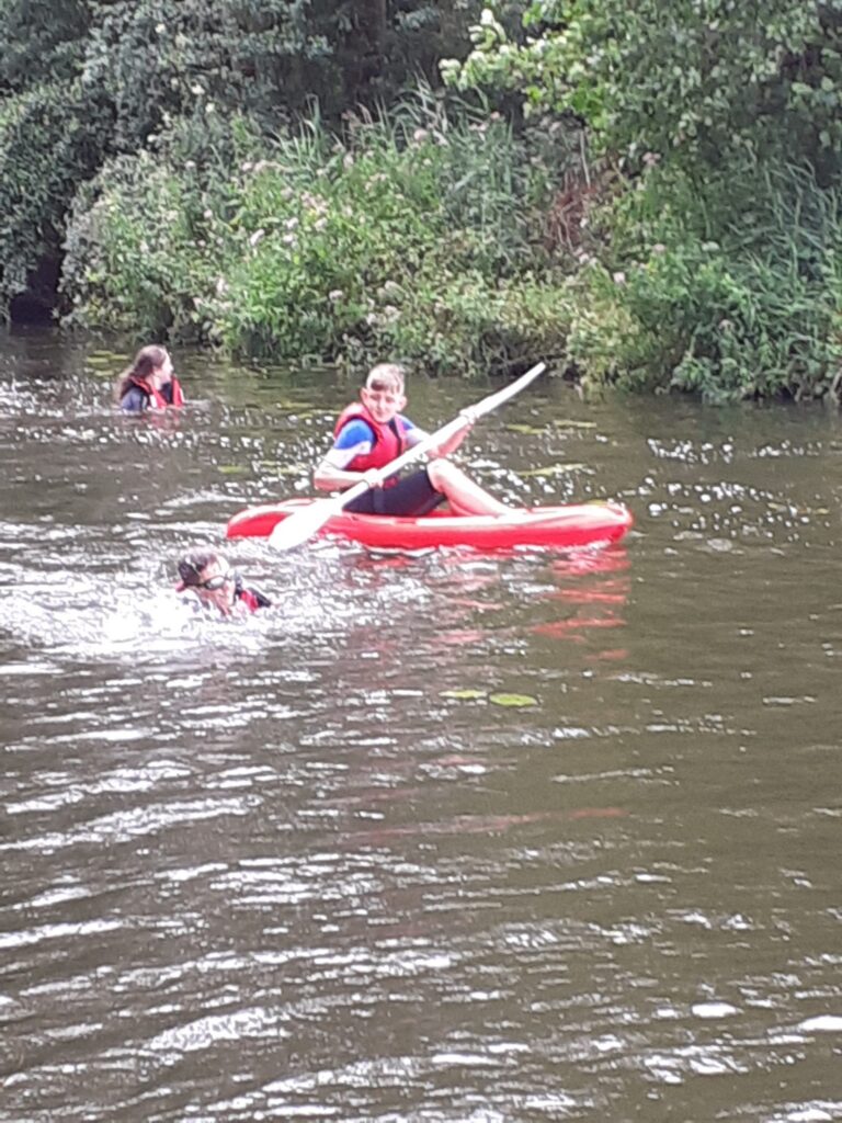 Kayaker paddling along a wooded stretch of water.