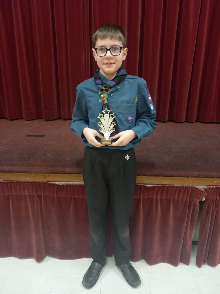 Scout in uniform holding a trophy.