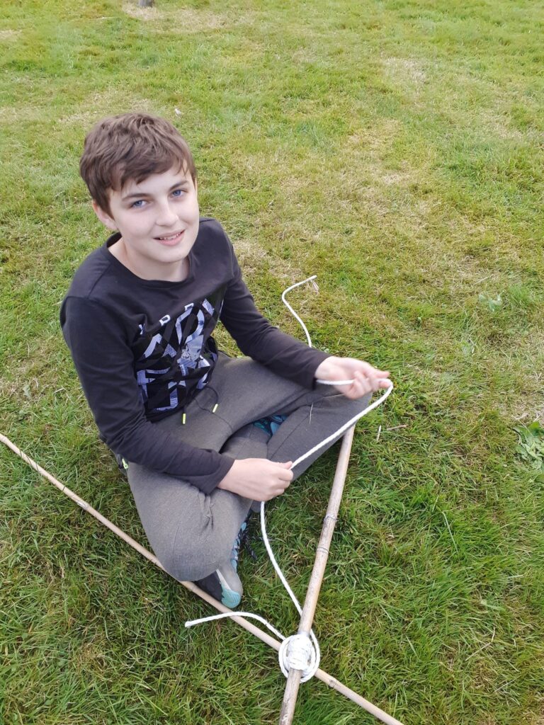 Scout practising knots outdoors with white rope.