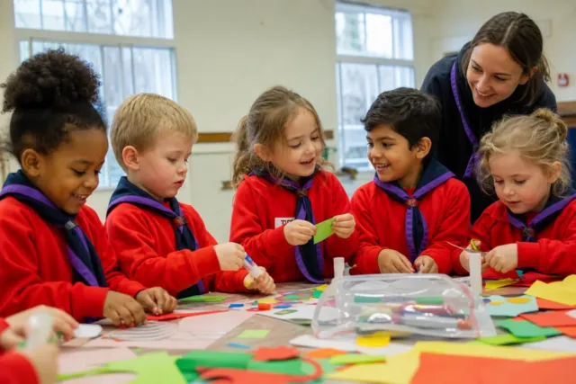 Squirrel Scouts aged four to six making crafts together in their red uniforms