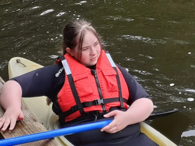 Kayaker wearing a red buoyancy aid and holding a paddle.