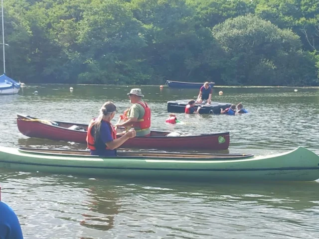 Scouts paddling canoes and kayaks together on the water.