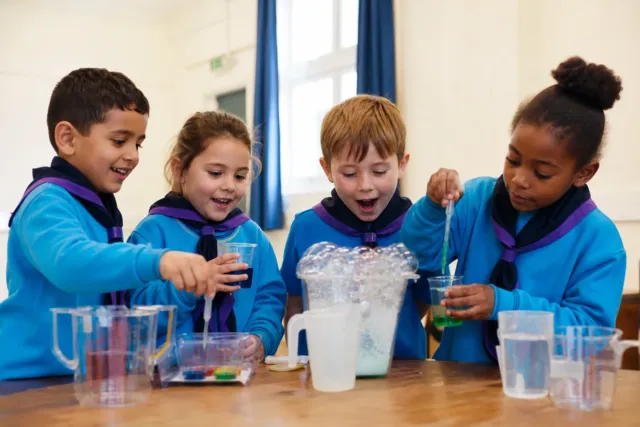 Beaver Scouts aged six to eight enjoying a science experiment in turquoise uniforms